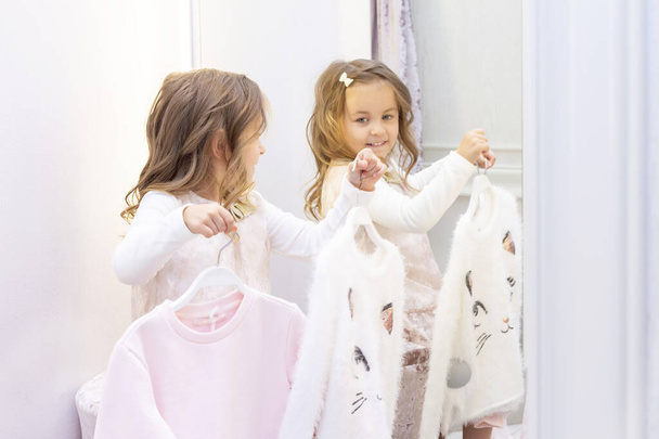 shopping. discounts. little girl shopaholic. girl trying on a beautiful dress gently pink in the fitting room of the boutique. shopping center, shopping. emotions - Φωτογραφία, εικόνα