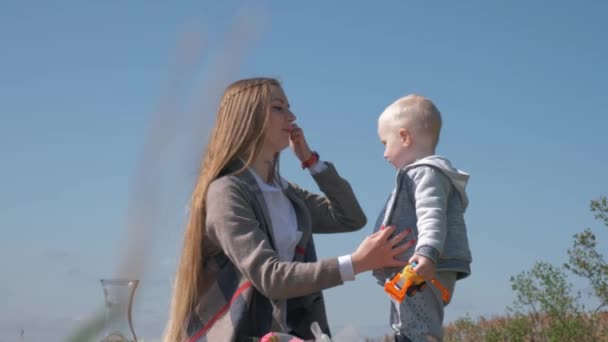 rakkaus äidille, pieni makea pikkulapsi poika suutelee äitiä piknikillä ulkona
 - Materiaali, video