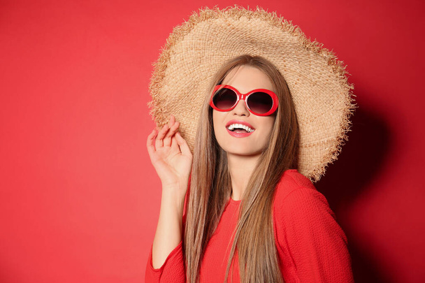 Young woman wearing stylish sunglasses and hat on red background. Space for text - Valokuva, kuva