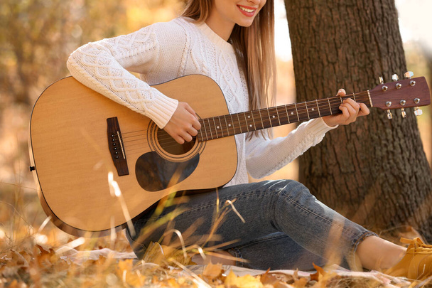 Teen girl playing guitar in autumn park, closeup - Foto, Bild
