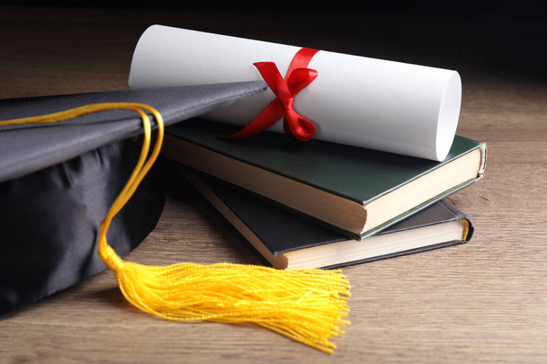 Graduation hat, books and student's diploma on wooden table - Foto, Bild