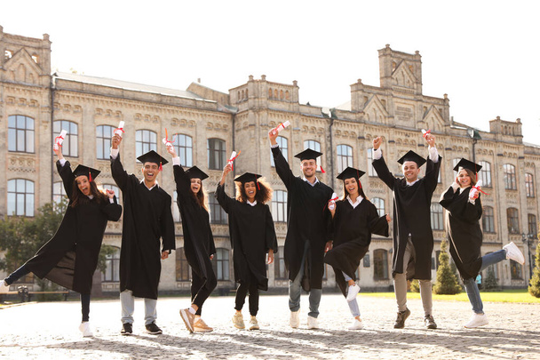 Happy students with diplomas outdoors. Graduation ceremony - Фото, зображення