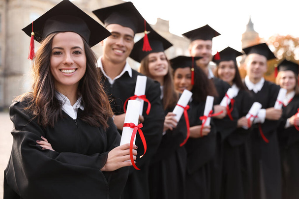 Happy students with diplomas outdoors. Graduation ceremony - Foto, imagen
