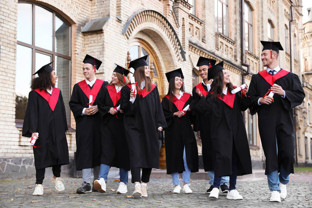Happy students with diplomas outdoors. Graduation ceremony - Фото, изображение