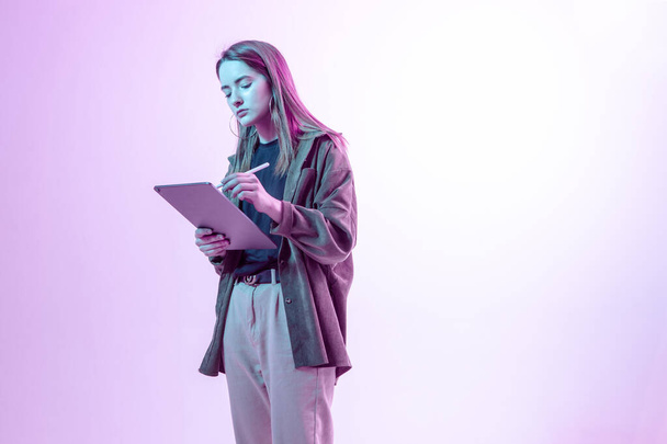Modern Girl with laptop, tablet computer. Free creativity. A young blogger makes a Home office. Colored Neon light. - 写真・画像