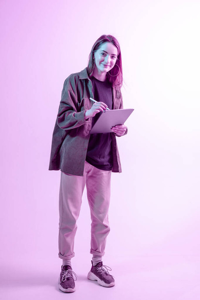 Garota moderna com laptop, computador tablet. Criatividade livre. Um jovem blogueiro faz um Home office. Luz de néon colorida
. - Foto, Imagem