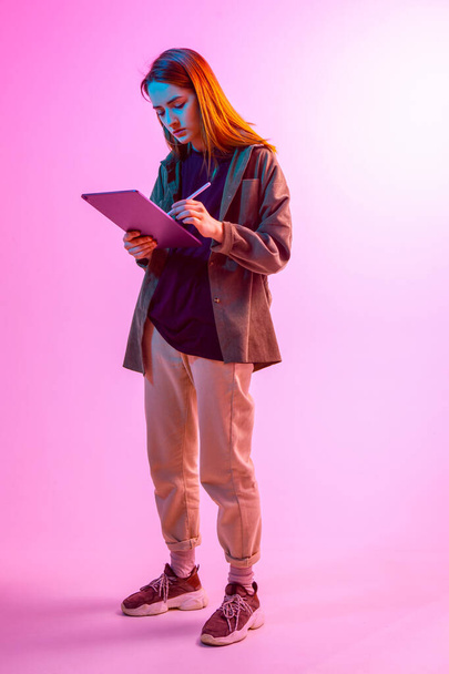 Modern Girl with laptop, tablet computer. Free creativity. A young blogger makes a Home office. Colored Neon light. - Fotografie, Obrázek