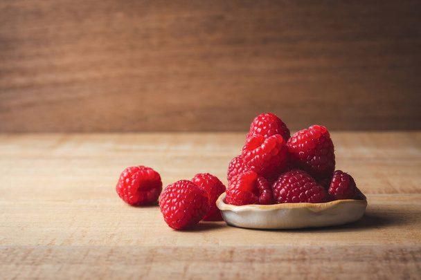 Fresh raspberries in ceramic bowl on wooden background. - Fotoğraf, Görsel