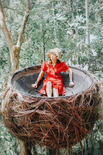 Mujer asiática bonita está sentada en nido de paja, Ubud, Bali. - Foto, imagen