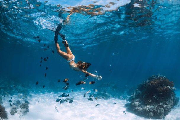 Fiatal nő szabad búvár bikini siklik át homokos tenger halak. Szabadúszó Hawaii-on. - Fotó, kép