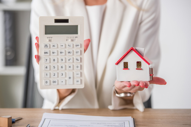 częściowy widok businesswoman pokazuje model domu i kalkulator - Zdjęcie, obraz
