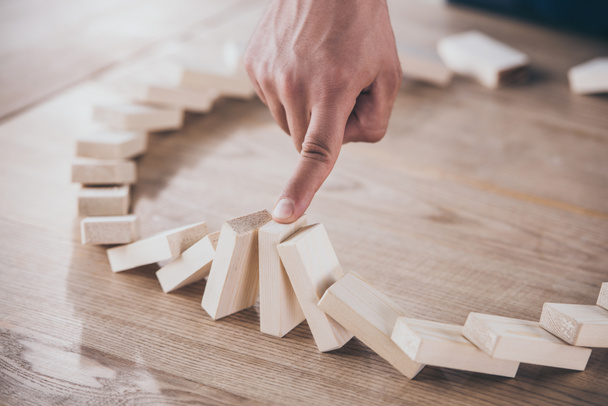 cropped view of businessman stopping domino effect of falling wooden blocks - Photo, Image