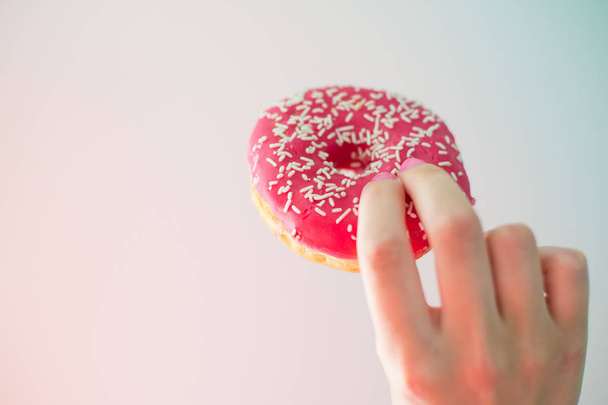Donut rosa na mão, close-up, fundo colorido
 - Foto, Imagem