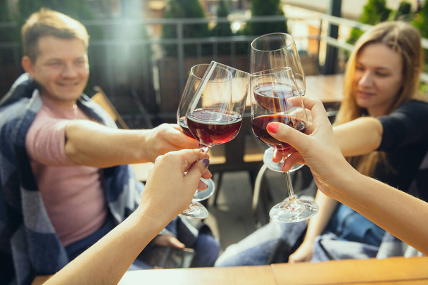 People clinking glasses with wine on the summer terrace of cafe or restaurant. Close up shot, lifestyle. - Foto, Imagem