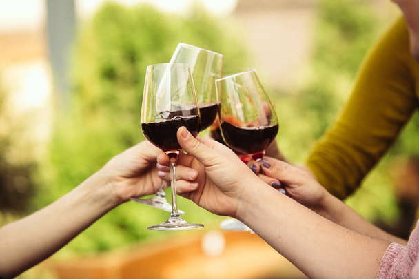 Lidé cinkající sklenicemi s vínem na letní terase kavárny nebo restaurace. Zblízka záběr, životní styl. - Fotografie, Obrázek