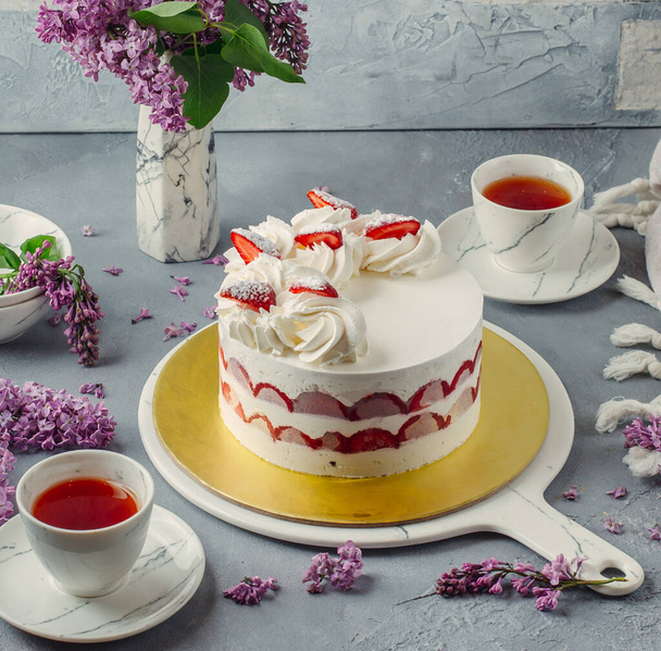 strawberry cake with whipped white cream with strawberry pieces, served with tea - Foto, immagini