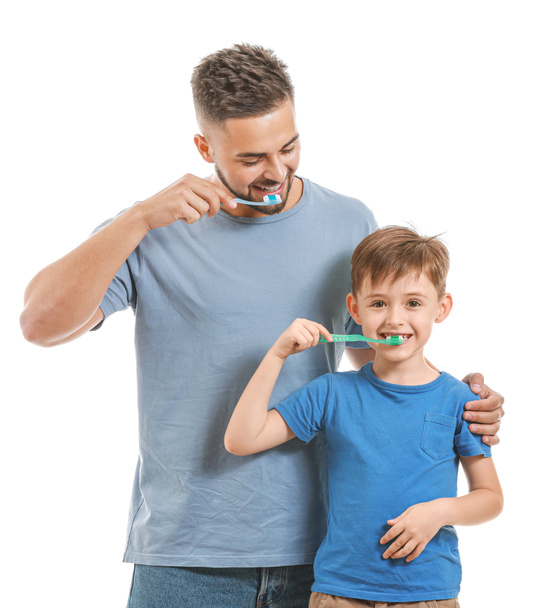 Portrait of father and his little son brushing teeth on white background - Foto, Imagen