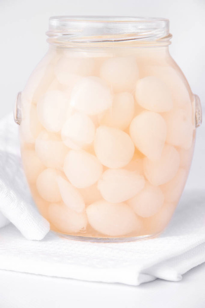 Ζυμωμένα κρεμμύδια σε ένα βάζο σε ελαφρύ φόντο. Ζυμωμένα τρόφιμα - Φωτογραφία, εικόνα