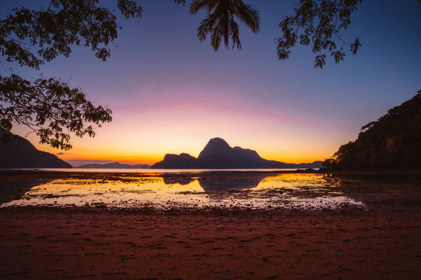 Puesta de sol en una isla tropical con silueta de palmeras. Bahía El Nido. Filipinas
 - Foto, imagen