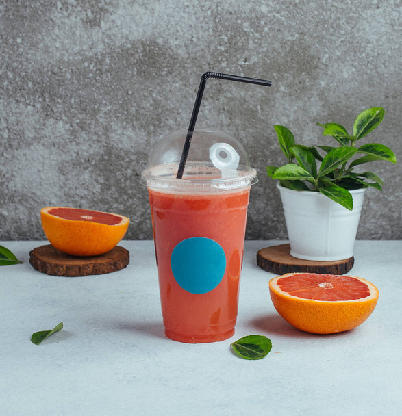 middle size plastic cup of fresh grapefruit juice with black straw - Foto, imagen