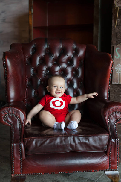 A little boy sits in a leather chair. Happy family life. Man was born. - Photo, Image