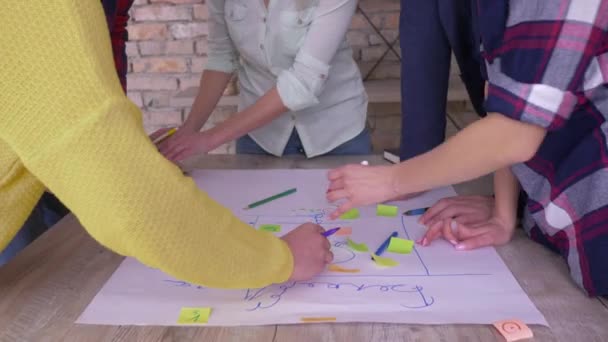 Creative teamwork, hands of office employees close up make up new project development business idea on big paper with stickers at table in modern office - Video, Çekim