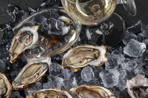 Verse geopende oesters in ijs op een zwarte getextureerde achtergrond. Bovenaanzicht. Close-up opname. - Foto, afbeelding