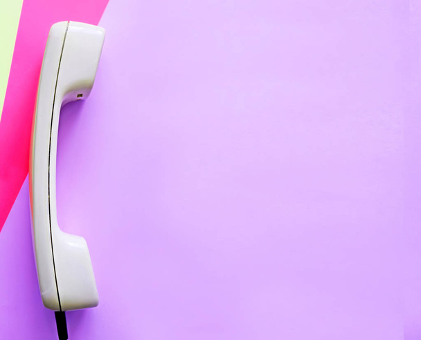 Білий старий телефон на барвистому фіолетовому, рожевому та жовтому тлі. Місце для тексту
 - Фото, зображення