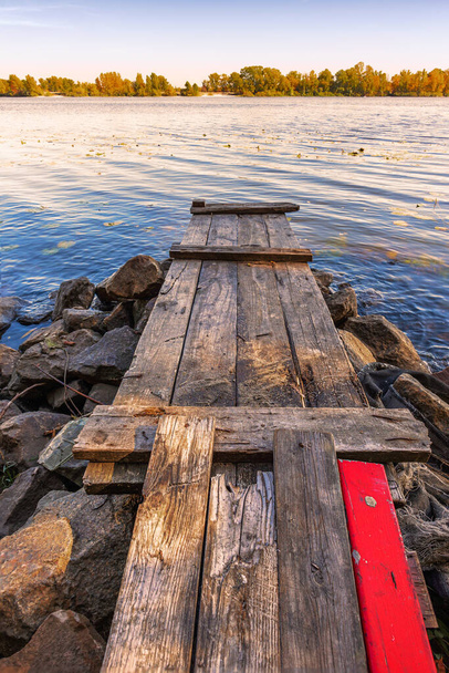 Houten ponton met een rode plank aan de rivier de Dnjepr - Foto, afbeelding