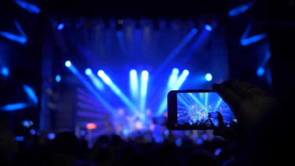 arms of fans with smartphones make photo and video recording at rock concert in stage floodlight in night - Footage, Video