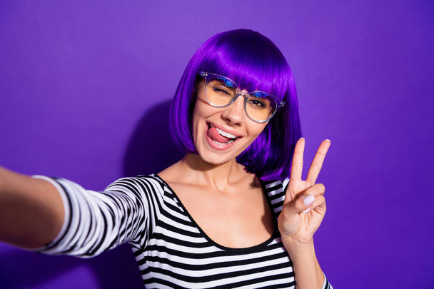 Portrait of charming youth making v-signs photo having trip wearing striped shirt isolated over purple violet background - Foto, imagen