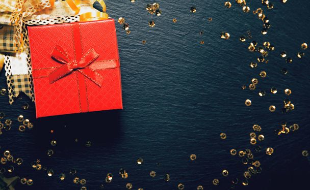 Caja de regalo roja sobre fondo negro con lentejuelas doradas. Chris.
 - Foto, imagen