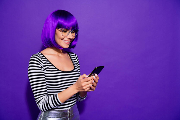 Portrait of charming youngster using modern technology reading news isolated over purple violet background - Foto, immagini