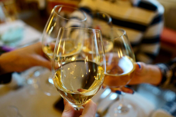 Viini lasit valkoviiniä ravintolassa. Ihmiset kolistelevat viinilaseja syntymäpäiväjuhlassa. kädet ilman ihmisiä
 - Valokuva, kuva