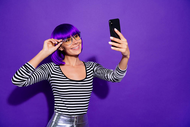 Pretty lady hold telephone taking selfies speaking skype best friend wear specs striped pullover isolated purple background - Photo, image
