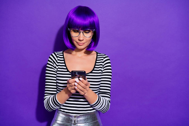 Photo of pretty lady holding hands new telephone writing email friends wear specs striped pullover isolated purple background - 写真・画像