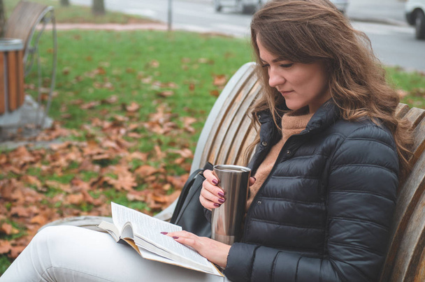 La chica tiene el libro en sus manos. La chica sentada en un banco, leyendo un libro
.  - Foto, imagen