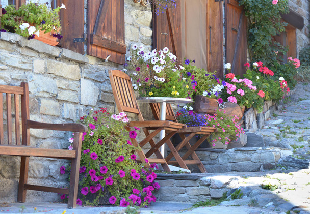 kolorowe kwiaty doniczkowe i krzesła przed fasadą alpejskiego domu w miejscowości  - Zdjęcie, obraz