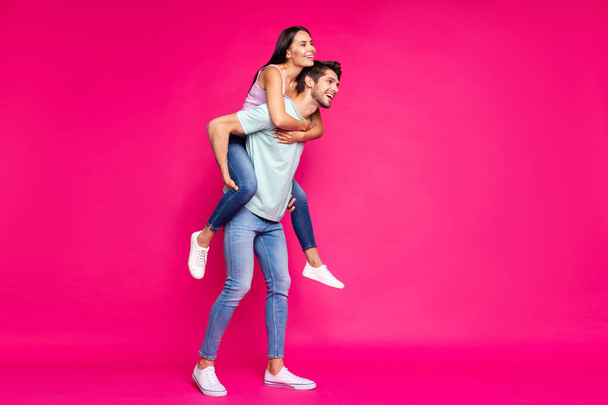 Full body photo of funny guy and lady holding piggyback spending free time looking far away wear casual clothes isolated vibrant pink color background - Fotografie, Obrázek