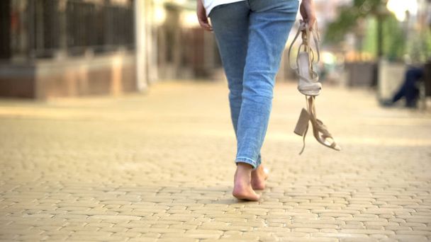 Barefoot girl walking down street holding in hands high-heeled sandals, freedom - Photo, image