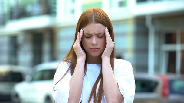 Tired girl with migraine rubbing temples, stress from living in noisy city, pms - 写真・画像