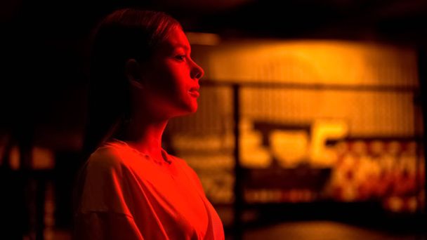 Beautiful girl waiting for friends or boyfriend in red light of night-club - 写真・画像