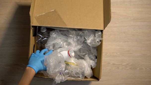 Drop-off station werknemer in handschoenen controleren plastic Prullenbak in doos, verminderen afval - Foto, afbeelding