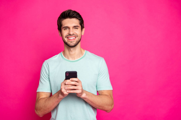 Photo of blogger guy holding telephone in hands checking subscribers toothy smiling wear casual outfit isolated vivid pink color background - Valokuva, kuva
