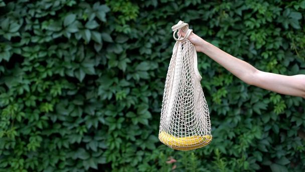 Hand demonstrating banana in crochet bag, reducing usage of plastic bags, reuse - Fotoğraf, Görsel