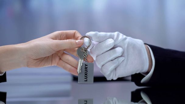 Hotel receptionist hand giving visitor keychain, top-quality service, luxury - Zdjęcie, obraz