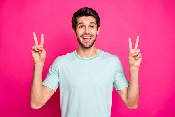 Photo of funny macho guy showing v-sign symbol saying hello to best friends wear casual t-shirt isolated vibrant pink color background - Foto, afbeelding