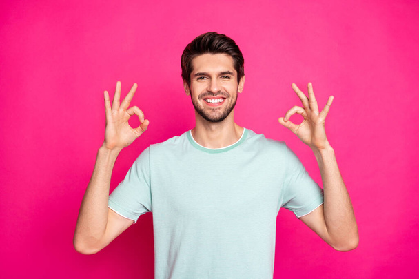 Photo of funny macho guy showing okey symbol expressing agreement and positive attitude wear casual t-shirt isolated vibrant pink color background - Zdjęcie, obraz