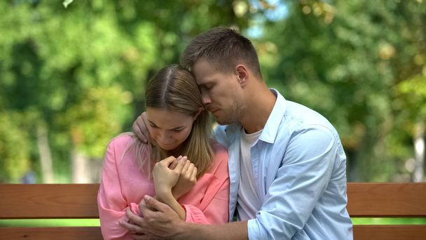 Loving husband comforting crying wife outdoors, family care, couple support - Foto, Imagen