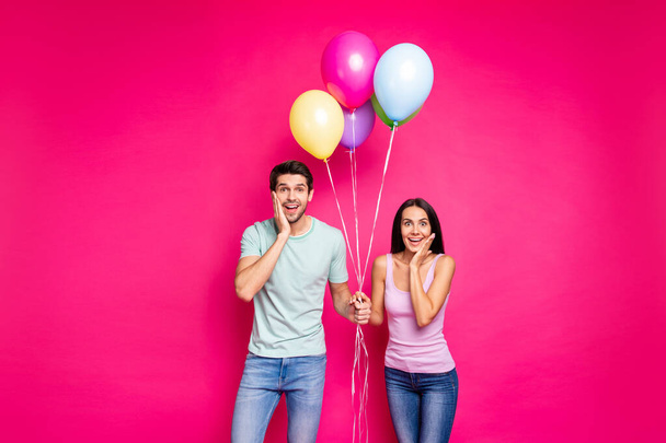 Photo of funny guy and lady holding air balloons arms on cheeks not believe unexpected surprise from friends wear casual outfit isolated pink color background - Foto, afbeelding